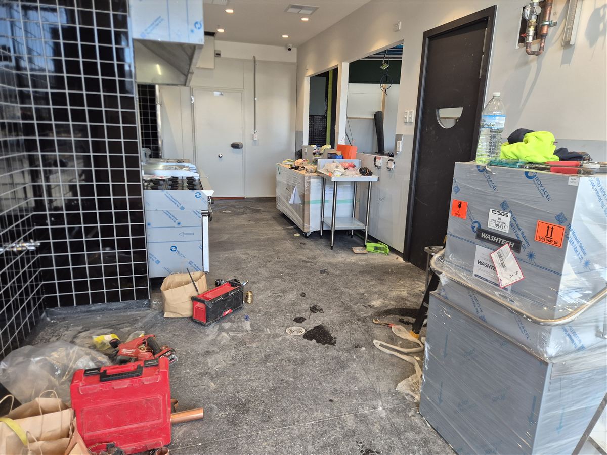 Construction dust and loose materials on a café kitchen floor before cleaning